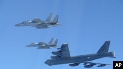 资料照片：这张由日本防卫省提供的照片显示，日本航空自卫队的F-15战斗机在日本领空附近与美国B-52轰炸机进行了联合军事演习。(2025年12月10日)