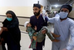 People carry a girl, who was injured in bus and train accident, after receiving initial treatment at a hospital in Sheikhupura near Lahore, Pakistan, July 3, 2020.
