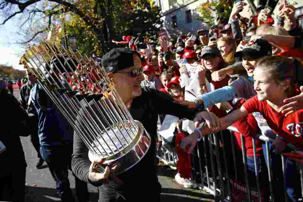 El gerente general de los Washington Nationals, Mike Rizzo, muestra el trofeo a los asistentes al desfile.