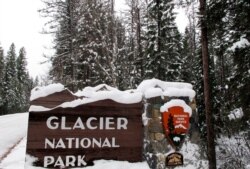 FILE - Snow covers the entrance sign to Glacier National Park in West Glacier, Mont., Dec. 11, 2012.