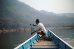 FILE - A local villager drives a boat where the future site of the Luang Prabang dam will be on the Mekong River, on the outskirts of Luang Prabang province, Laos, Feb. 5, 2020.