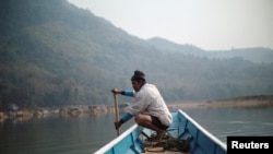FILE - A local villager travels by boat where the future site of the Luang Prabang dam will be on the Mekong River, outskirt of Luang Prabang province, Laos, Feb. 5, 2020.