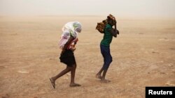 Women wrapped in shawls walk through a sandstorm in Timbuktu, July 29, 2013.