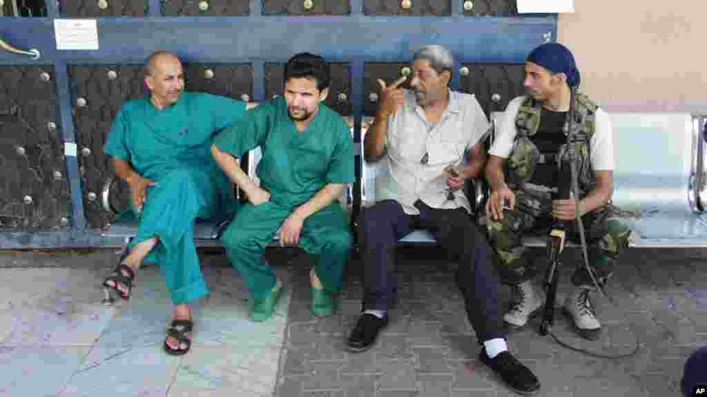 Doctors, left, take a break outside the Zawiya hospital. (VOA Photo - E. Arrott)