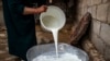 FILE - A farmer empties a bucket of water buffalo milk into a metal bowl in Syria's Kurdish-controlled northeastern Hasakah province, May 28, 2023. Buffalo milk is creating controversy in Pakistan as the country finalizes an agreement with China to export the product. 