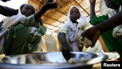 Internally displaced schoolchildren eat from the same bowl during a feeding program provided by the World Food Program at the Abushouk camp in Al Fasher in North Darfur, Sudan, Nov. 17, 2015.