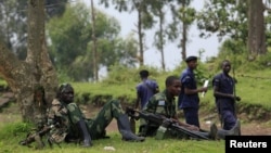 M23 rebel fighters watch the venue of a news conference by political leader Jean-Marie Runiga, in Bunagana, eastern DRC, in north Kivu province, July 21, 2012.