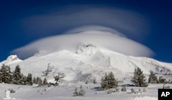 FILE - In this Dec. 14, 2009, file photo, a large cloud caps Mount Hood where the search for two missing climbers continues as seen from Timberline Lodge in Government Camp, Ore. (AP Photo/Don Ryan, File)
