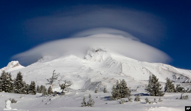 FILE - In this Dec. 14, 2009, file photo, a large cloud caps Mount Hood where the search for two missing climbers continues as seen from Timberline Lodge in Government Camp, Ore. (AP Photo/Don Ryan, File)