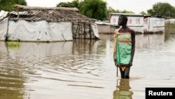 Seorang anak perempuan berjalan mengarungi banjir setelah hujan lebat dan banjir memaksa ribuan orang mengungsi dari tempat tinggal mereka di Pibor, negara bagian Boma, Sudan Selatan, 6 November 2019.