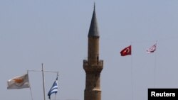 Bendera Siprus dan Yunani berkibar bersebelahan denan Bendera Turki dan Siprus-Turki dekat zona penyangga yang berada di bawah kendali PBB di Nikosia, Siprus, 6 Juli 2017 (foto: REUTERS/Yiannis Kourtoglou)