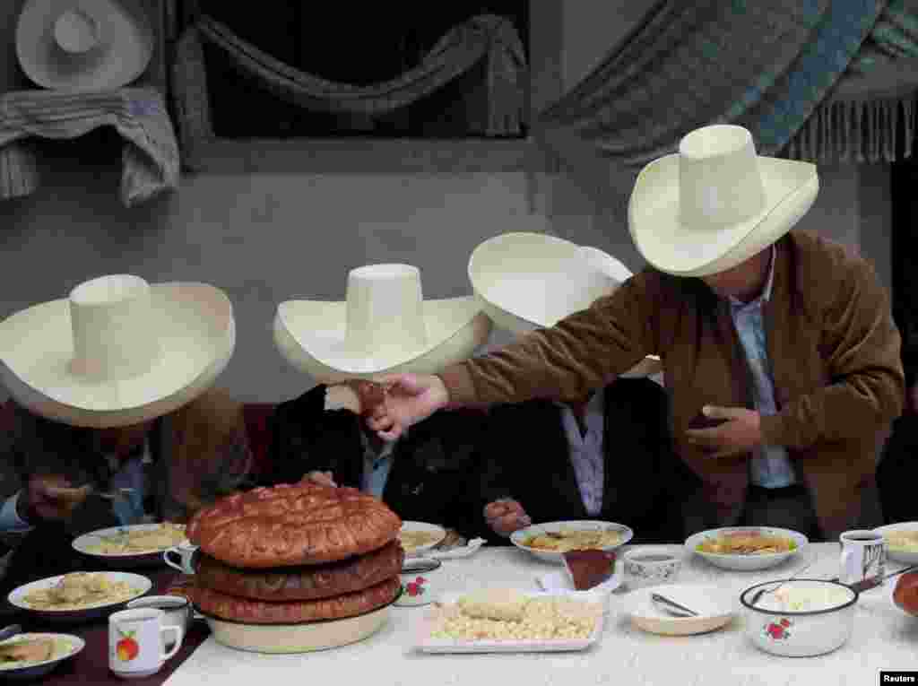 Peru&#39;s presidential candidate Pedro Castillo (R) hands over bread during a breakfast with members of his family before casting his vote in Chugur.