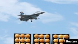 A Taiwan Air Force F-16 fighter jet flies above a Thunderbolt-2000, a wheeled Multiple Launch Rocket System (MLRS) during a performance at Gangshan air force base in Kaohsiung, Taiwan August 7, 2017. 