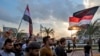 Iraqi protesters march with national flags and a Shiite Muslim flag during an anti-government demonstration in the southern Iraqi city of Basra on Nov. 29, 2019. 