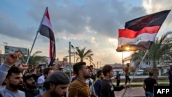 Iraqi protesters march with national flags and a Shiite Muslim flag during an anti-government demonstration in the southern Iraqi city of Basra on Nov. 29, 2019. 