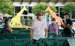 FILE - Patrons wearing masks to help prevent the spread of the new coronavirus wait in line to enter Zoo Miami, Sept. 15, 2020, in Miami.