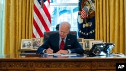 FILE - President Joe Biden signs a series of executive orders on health care, in the Oval Office of the White House, Jan. 28, 2021.