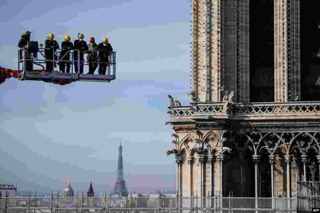 Workers on a crane look at Notre-Dame cathedral site in Paris, France.