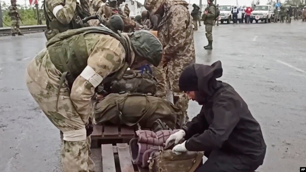 俄罗斯国防部2022年5月19日公布的视频截图显示俄罗斯军人在乌东顿涅茨克亲俄政权控制区检查离开马里乌波尔亚速钢铁厂的乌克兰军人的随身物品。(photo:VOA)
