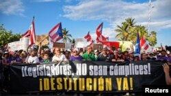 Los manifestantes cantan y ondean banderas puertorriqueñas durante el quinto día de protesta pidiendo la renuncia del gobernador Ricardo Rossello en San Juan, Puerto Rico.