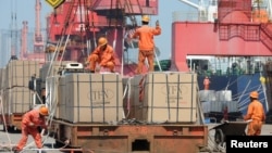 FILE - Workers load goods for export onto a crane at a port in Lianyungang, Jiangsu province, China, June 7, 2019. 