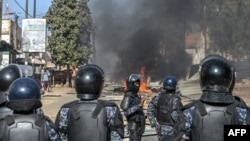 Senegalese police officers stand in formation on a road blocked with burning barricades during demonstrations called by the opposition parties in Dakar on February 4, 2024.