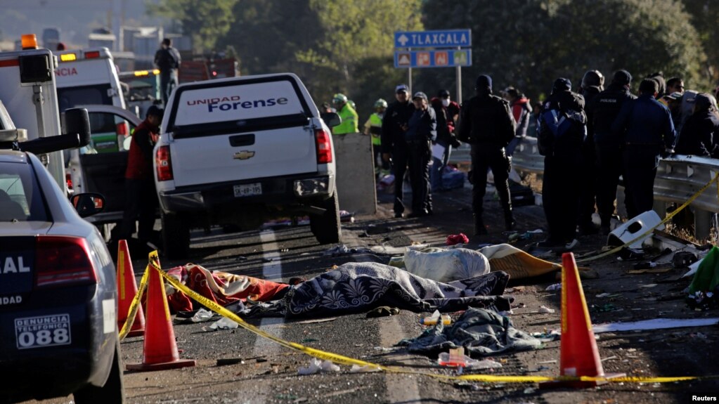 FILE - Police officers and rescue personnel stand near the bodies of people who were killed in a car crash on the outskirts of Puebla, Mexico, Dec. 12, 2017.