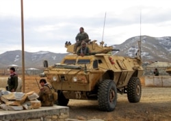 FILE - Afghan National Army soldiers keep watch outside of a military compound after a car bomb blast on the outskirts of Ghazni city, Afghanistan, Nov. 29, 2020.