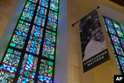In this Feb. 12, 2019 photo, a banner hangs by a stained glass window in the sanctuary at Glide Memorial United Methodist Church in San Francisco.