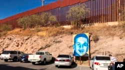 FILE - This is the boundary between the U.S. and Mexico at Nogales, Mexico, Dec. 4, 2017. The poster is of Juan Antonio Elena Rodriguez, a teen who was shot and killed by a Border Patrol agent who shot through the fence in 2010. 