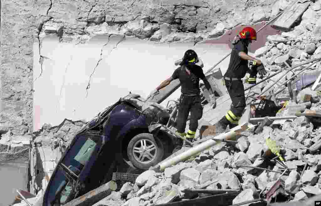 Petugas penyelamat berusaha mencari korban gempa di antara reruntuhan bangunan di Pescara Del Tronto, Italia.