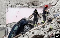 Rescuers make their way through destroyed houses following Wednesday's earthquake in Pescara Del Tronto, Italy, Aug. 25, 2016.