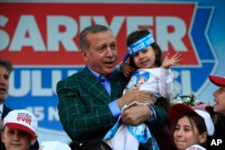 Turkey's President Recep Tayyip Erdogan holds a young girl during his last rally ahead of Sunday's referendum, in Istanbul, April 15, 2017.