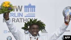 Eliud Kipchoge célèbre son trophée sur le podium du marathon de Berlin, Allemagne, le 16 septembre 2018 à Berlin.