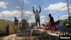 A man stands on a burned car as supporters of Kenya's opposition leader Raila Odinga participate in an anti-government protest against the imposition of tax hikes by the government in Nairobi, Kenya July 20, 2023. 