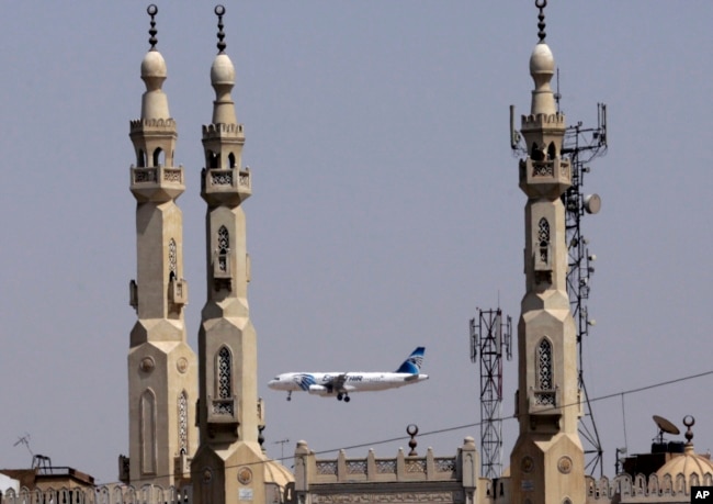 FILE - In this May 21, 2016, file photo, an EgyptAir plane flies past minarets of a mosque as it approaches Cairo International Airport, in Cairo, Egypt.