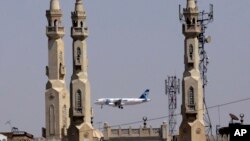 Un avion d'EgyptAir passe devant les minarets d'une mosquée alors qu'il s'approche de l'aéroport international du Caire, au Caire, en Égypte, le 21 mai 2016. (AP Photo/Amr Nabil)