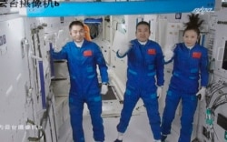 Screen image captured at Beijing Aerospace Control Center in Beijing, China, Oct. 16, 2021, shows three Chinese astronauts waving after entering the space station core module Tianhe.