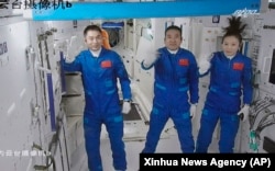 Screen image captured at Beijing Aerospace Control Center in Beijing, China, Oct. 16, 2021, shows three Chinese astronauts waving after entering the space station core module Tianhe.