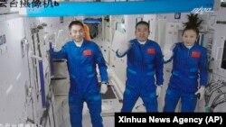 Screen image captured at Beijing Aerospace Control Center in Beijing, China, Oct. 16, 2021, shows three Chinese astronauts waving after entering the space station core module Tianhe.