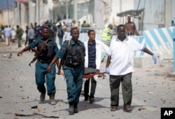 United Nations office guards and Somalian soldiers carry the dead body of their colleague who was killed in a suicide car bomb outside the UN's office in Mogadishu, Somalia on July 26, 2016