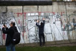 Tourist take photos at the remains of the Berlin Wall after commemorations celebrating the 30th anniversary of its fall, at Bernauer Strasse in Berlin, Nov. 9, 2019.