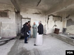 Ahmed Hashem was displaced from his home in Idlib, Syria, several times. Here, he speaks to Heather Murdock and Halan Akoiy in a complex refugees now occupy after it was abandoned by IS militants, in Raqqa, Syria, Feb. 23, 2020. (Hamodi JwanKojo/VOA)