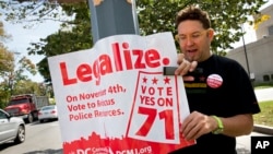 FILE - Adam Eidinger, chairman of the DC Cannabis Campaign, puts up posters encouraging people to vote yes on DC Ballot Initiative 71 to legalize small amounts of marijuana for personal use, in Washington, Oct. 9, 2014.