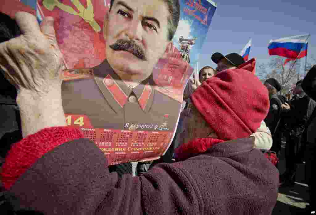 An elderly woman holds a calendar depicting Soviet leader Josef Stalin while watching a broadcast of Russian President Vladimir Putin&#39;s speech on Crimea, as thousands of pro-Russian people gathered to watch the address, in Sevastopol,&nbsp;Crimea, Ukraine, March 18, 2014. 