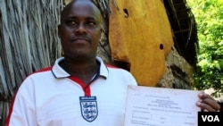 Felix Karisa hold up the notice ordering the eviction of his entire village outside Mombasa, Kenya, November 18, 2012. (H. Heuler/VOA)