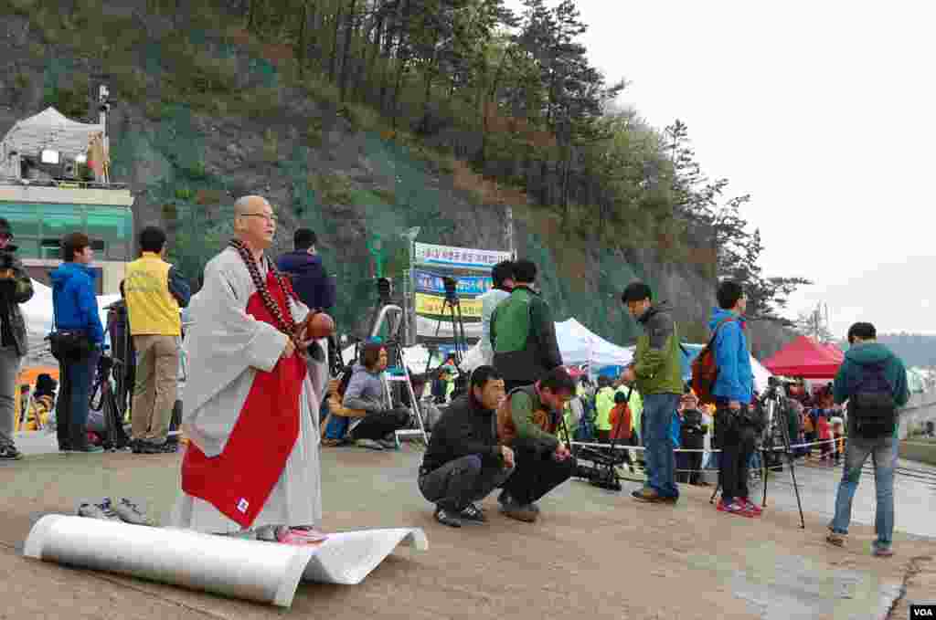 A Buddhist monk prays for the missing passengers who were on the South Korean ferry, Sewol. Family members, rescue staff and members of the press gather at the port, Jindo, April 18, 2014. (Sungmin Do/VOA)