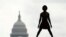 FILE - With the dome of the US Capitol in the background, a homeless man named Damu stretches on the National Mall in Washington, May 27, 2020. 