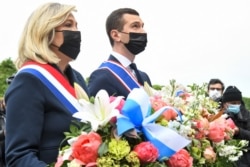 French far-right Rassemblement National (RN) party president Marine Le Pen (L) and French far-right party Rassemblement National eurodeputy Jordan Bardella lay a wreath of flowers in front of a statue of Joan of Arc in Paris, May 1, 2021.