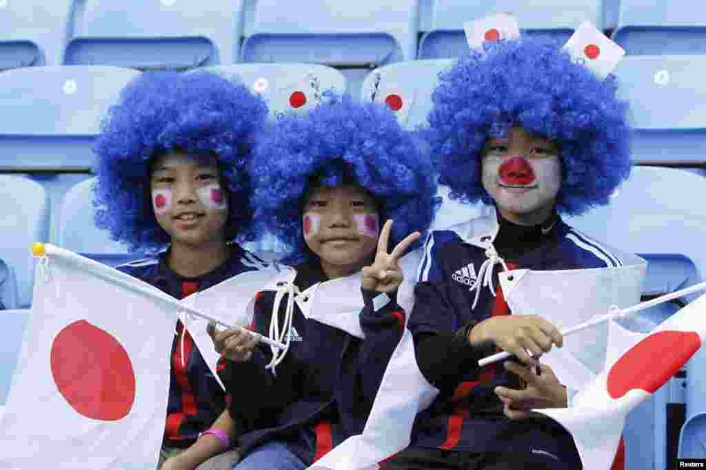 Fans dari Jepang tersenyum sebelum pertandingan sepak bola puteri tim Jepang melawan Swedia di stadion Coventry, 28 Juli 2012.